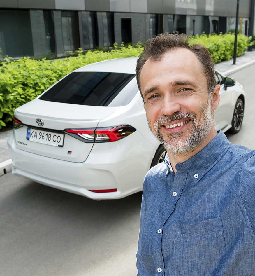 Усміхнений чоловік перед авто тойота
